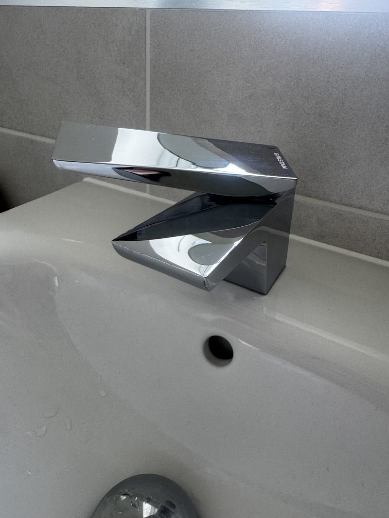 A bathroom tap and basin after cleaning